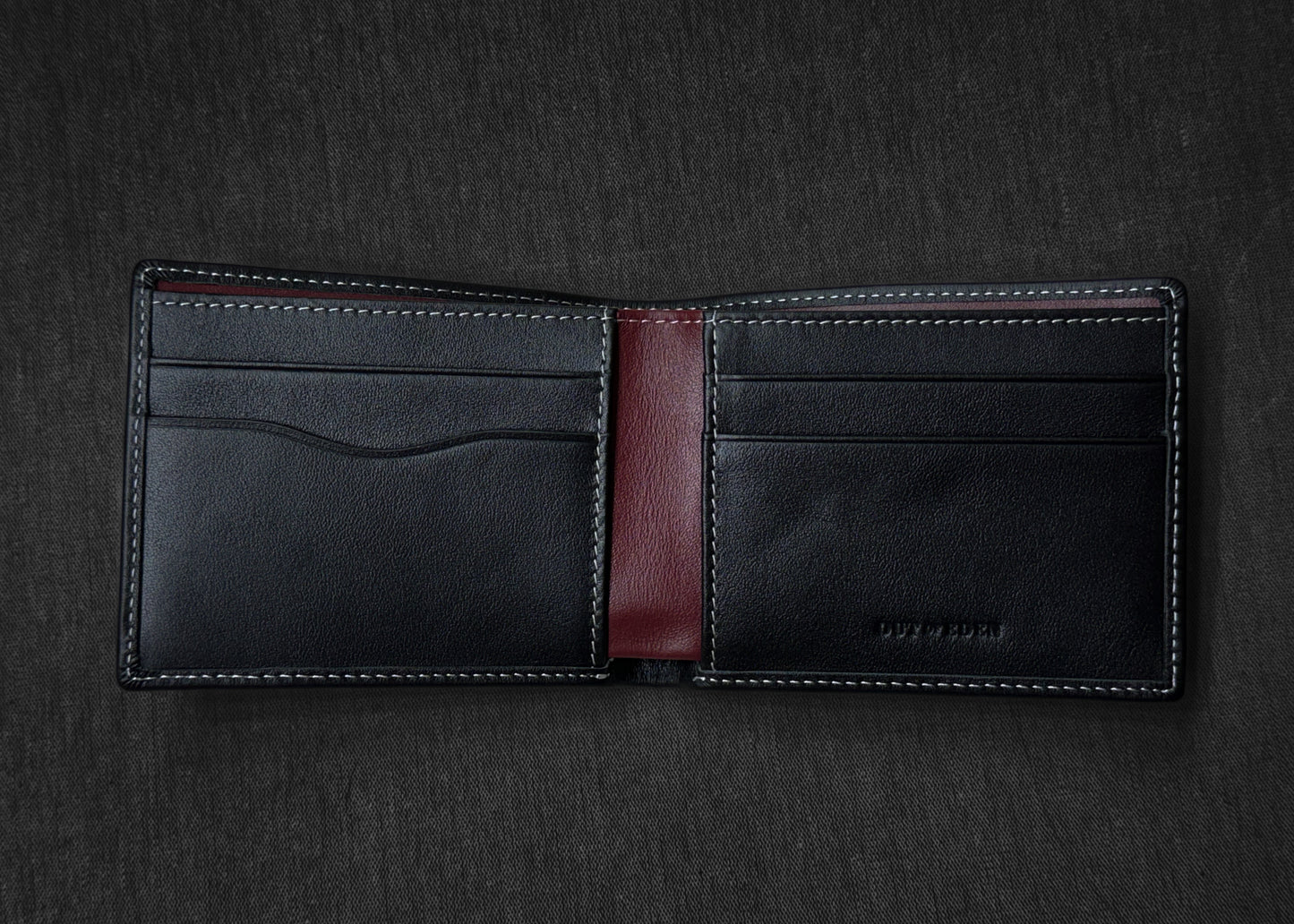 Black leather wallet with a red interior on a dark gray background
