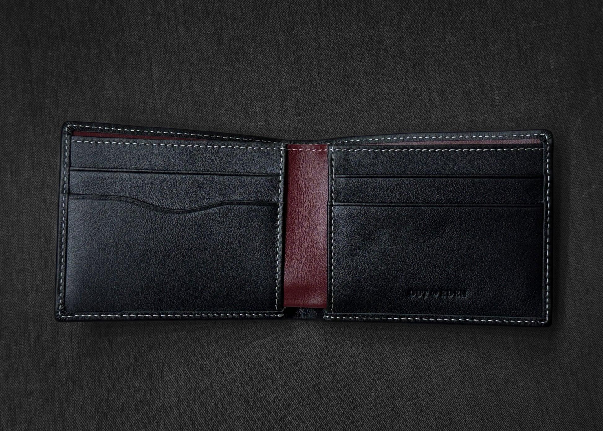 Black leather wallet with a red interior on a dark gray background
