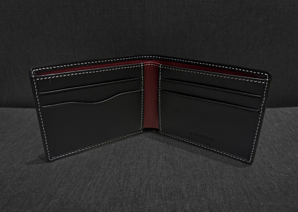 Black leather wallet with red interior on a dark gray background